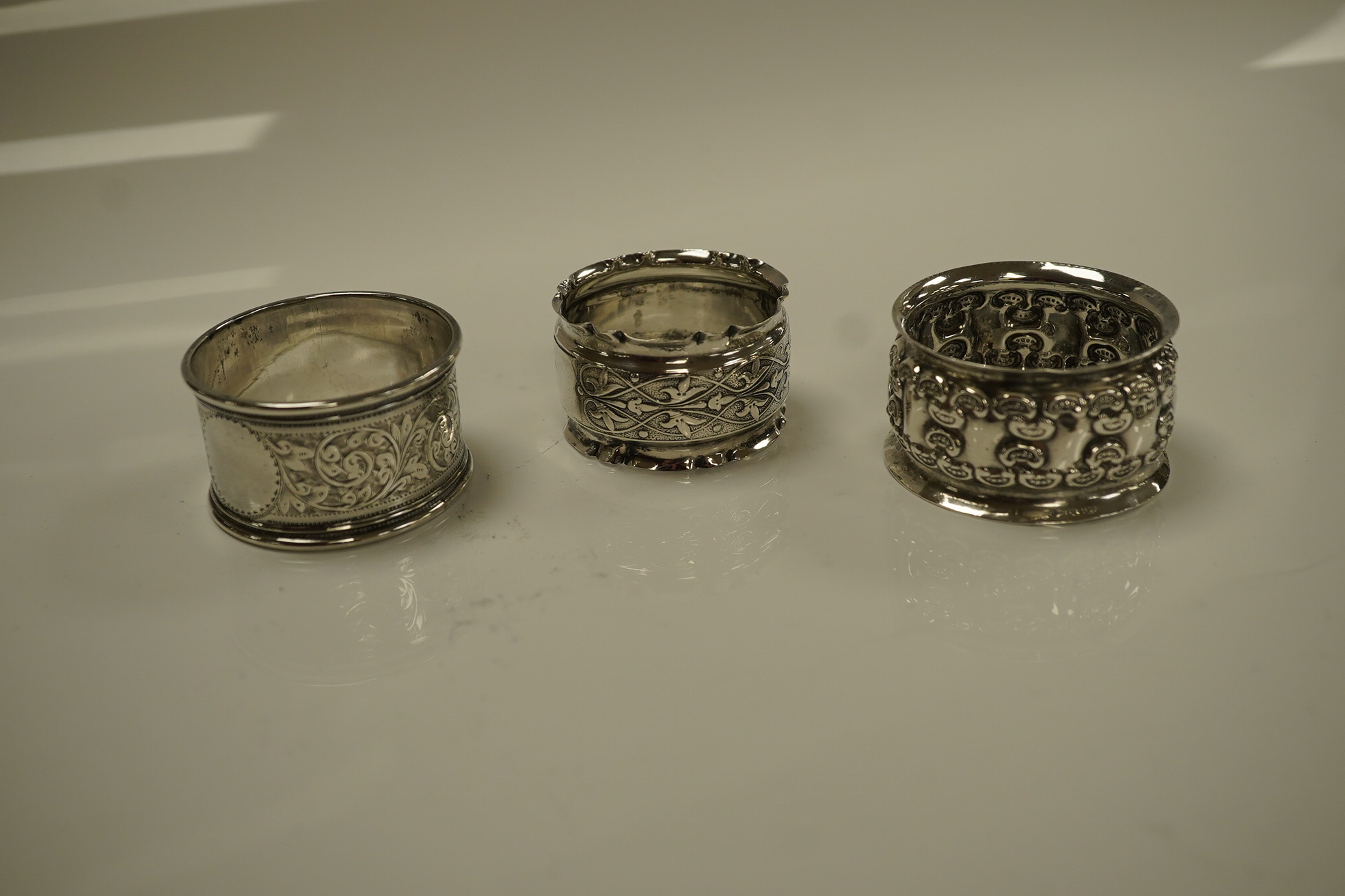 An Elizabeth II silver three piece condiment set, Sheffield, 1964, six assorted silver napkin rings and a stylish Austro Hungarian white metal pill box, by George Adam Scheid, 62mm. Condition - fair